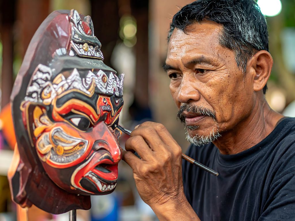 Artigiano che decora una maschera di legno